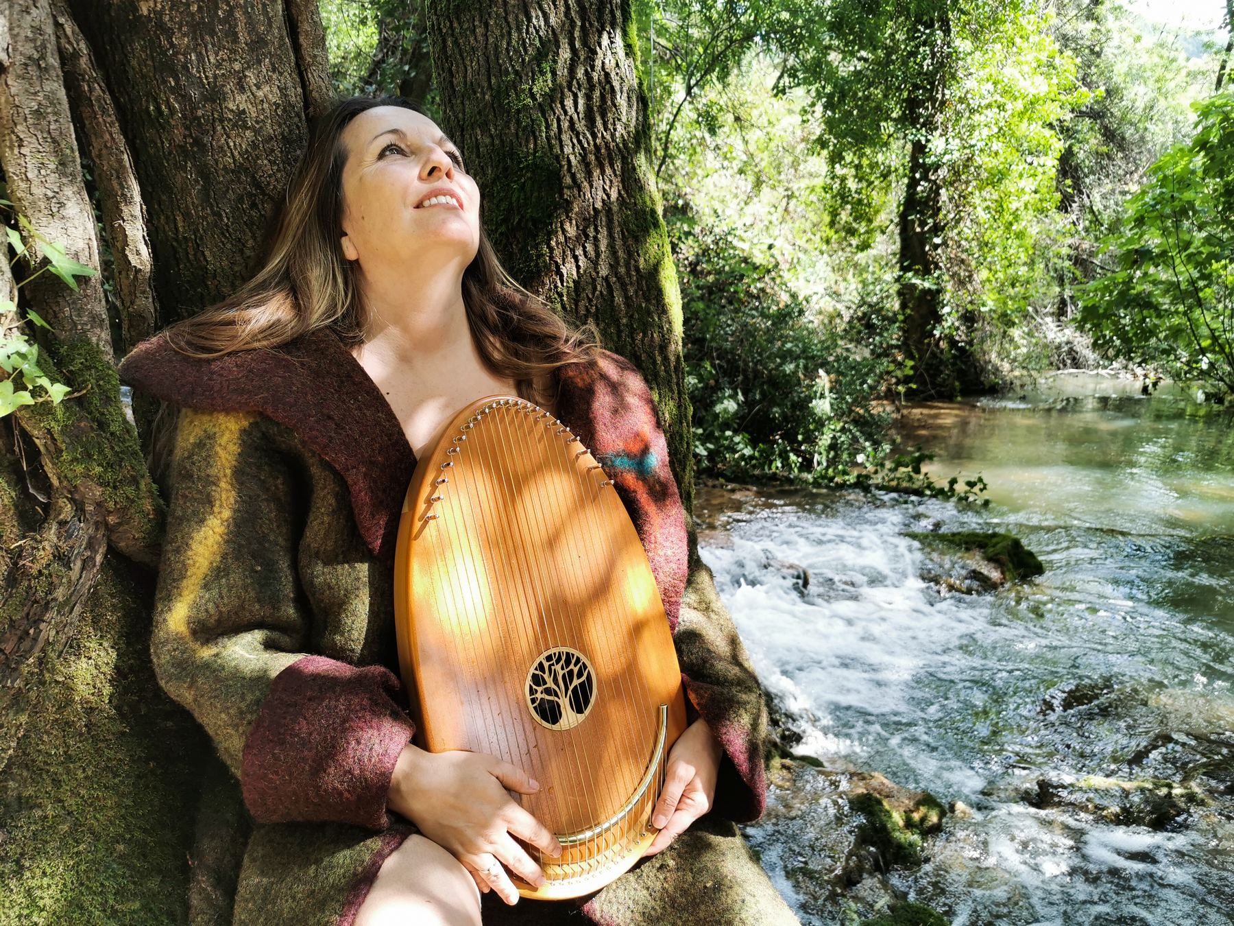 Une femme chante avec un tambour au bord d'une rivière